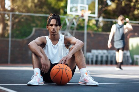 Téléchargez les photos : Le basket, c'est tout pour moi. Portrait d'un jeune homme sportif assis sur un terrain de basket - en image libre de droit