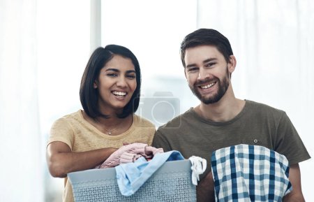 Téléchargez les photos : Des vêtements propres, une maison heureuse. un jeune couple faisant la lessive ensemble à la maison - en image libre de droit