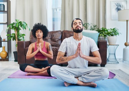 Téléchargez les photos : Le yoga a amélioré notre santé et notre relation. un jeune couple pratiquant le yoga dans leur salon - en image libre de droit