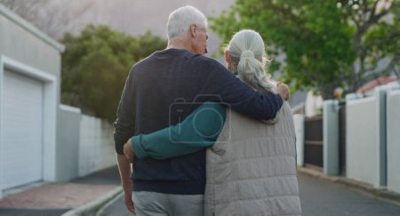 Foto de Un paseo fuera es todo lo que necesitábamos. una pareja de ancianos caminando por la calle afuera con sus brazos alrededor del otro - Imagen libre de derechos