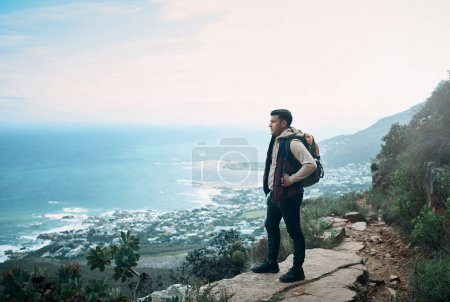 Foto de El sonido de la naturaleza es el mejor que hay. un joven mirando la vista desde un acantilado mientras estaba en una caminata - Imagen libre de derechos