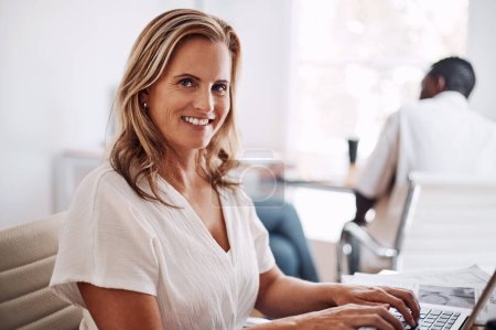 Photo for The hard work never ends. Cropped portrait of an attractive young businesswoman sitting in her office with her coworkers and using her laptop - Royalty Free Image