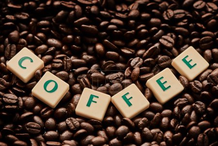 Téléchargez les photos : Le café me fait sourire. Gros plan de lettres moulées formant le mot café sur une pile de grains de café - en image libre de droit