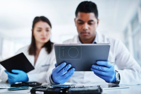Photo for Whats tech support without cutting edge technology. a young man and woman using a digital tablet while repairing computer hardware in a laboratory - Royalty Free Image