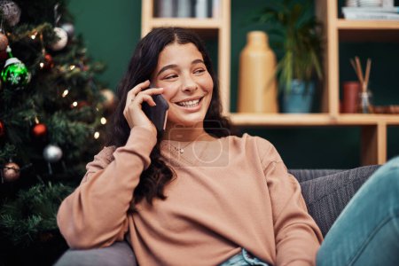 Photo for Just calling to say, Merry Christmas. a beautiful young woman using a smartphone on the sofa during Christmas at home - Royalty Free Image