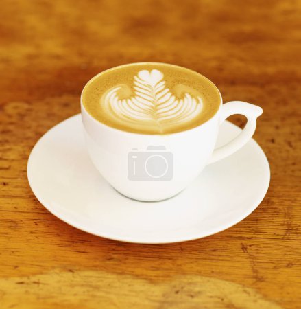 Foto de Café, café y arte latte en una taza sobre fondo de mesa de madera en el restaurante para beber espresso con espuma. Retro, comedor y taza con platillo en la cocina con diseño vintage durante el desayuno de la mañana - Imagen libre de derechos