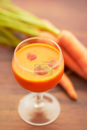 Photo for Carrot juice, vegetable and healthy food or drink with color, art and nutritionist creativity. Vegan smoothie or orange liquid in glass for wellness, diet or nutrition on a wooden table with ice. - Royalty Free Image