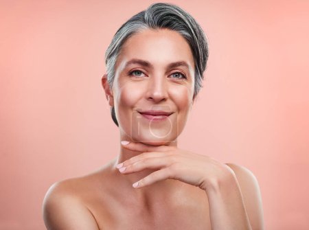 Photo for Im sure you want to know my secrets to beautiful skin. Studio portrait of a beautiful mature woman posing against a peach background - Royalty Free Image