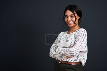 Photo for I am a strong woman in business. Cropped portrait of an attractive young businesswoman standing alone with her arms folded against a black background in the studio - Royalty Free Image
