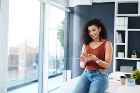 Photo for Opportunity didnt knock, I built the door. an attractive young businesswoman sitting alone in her office and texting on her cellphone - Royalty Free Image