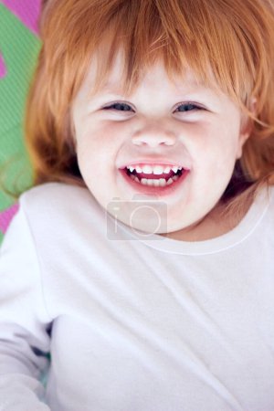Téléchargez les photos : Jeune fille, portrait drôle et drôle d'un bébé sur un terrain de jeux à la maison avec un sourire. Gingembre bébé, enfant rire et heureux dans une maison avec joie, la jeunesse et la positivité de l'enfance en levant les yeux. - en image libre de droit