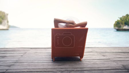 Foto de Encontré mi lugar de relajación perfecto. Vista trasera de una mujer irreconocible sentada en una tumbona sola durante unas vacaciones en Indonesia - Imagen libre de derechos