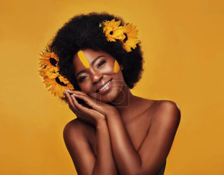 Foto de Abrazando belleza floral. Retrato de estudio de una hermosa joven sonriendo mientras posaba con girasoles en el pelo sobre un fondo de mostaza - Imagen libre de derechos