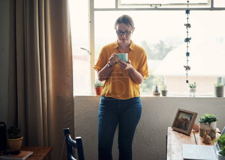 Photo for Coffee replenishes my soul. an attractive young businesswoman standing in her home office and holding a cup of coffee - Royalty Free Image