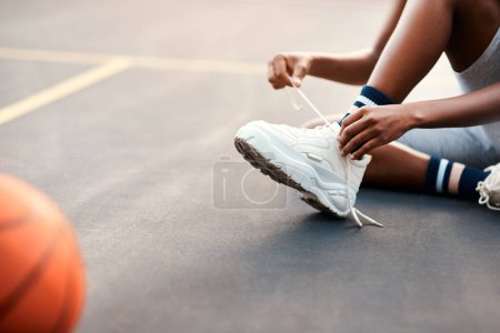 Photo for Making sure my laces are tied. an unrecognizable sportswoman sitting on the court and tying her shoelaces before playing a game of basketball - Royalty Free Image