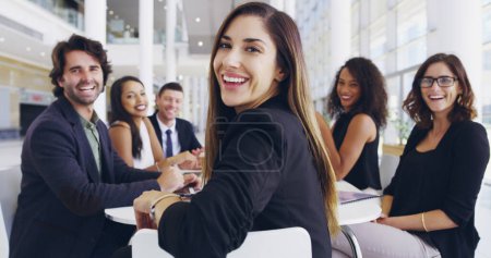 Foto de Todos bienvenidos. una joven empresaria sonriendo en una oficina durante una reunión con sus colegas de fondo - Imagen libre de derechos