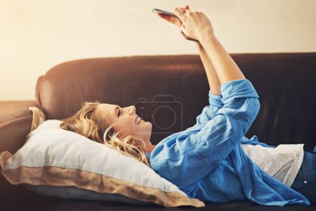 Téléchargez les photos : Il faut que cet angle soit juste. une jeune femme détendue utilisant un smartphone sur le canapé à la maison - en image libre de droit
