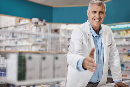 Foto de Bienvenido a la mejor farmacia de la zona. un farmacéutico extendiendo su brazo para un apretón de manos - Imagen libre de derechos