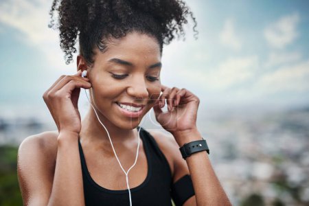Photo for Music helps me move faster. a sporty young woman listening to music while exercising outdoors - Royalty Free Image