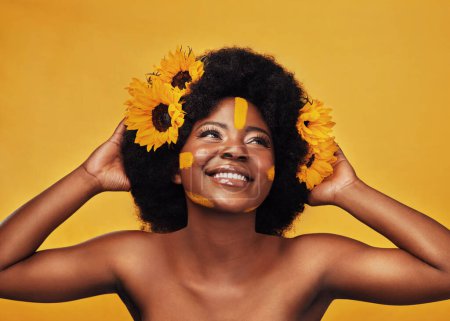 Photo for A sunflower on your hair equals a happy mood. Studio shot of a beautiful young woman smiling while posing with sunflowers in her hair against a mustard background - Royalty Free Image