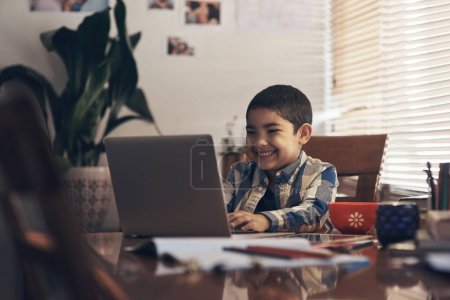 Photo for First lesson of the day is so much fun. an adorable little boy using a laptop while completing a school assignment at home - Royalty Free Image
