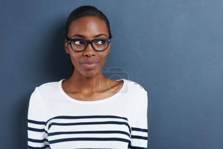 Photo for Happy, thinking and black woman with glasses, ideas and thoughtful against a blue studio background. Female person, lady and girl with eyewear, clear vision and thoughts with decision and opportunity. - Royalty Free Image