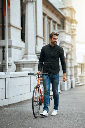 Foto de Moverse por la ciudad es más fácil en bicicleta. Foto completa de un joven guapo viajando con su bicicleta por la ciudad - Imagen libre de derechos