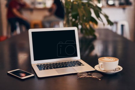 Foto de Es hora de aumentar la productividad. un ordenador portátil, café y teléfono inteligente en una mesa en un café - Imagen libre de derechos