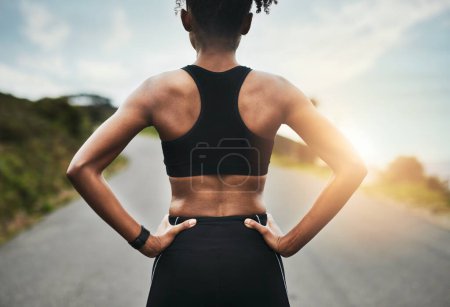 Photo for Shes got her goal in sight. Rearview shot of an unrecognizable young sportswoman standing with her hands on her hips outside - Royalty Free Image