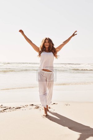 Téléchargez les photos : Célébrez la vie et tout dans la beauté en elle. une jeune femme debout les bras tendus à la plage - en image libre de droit