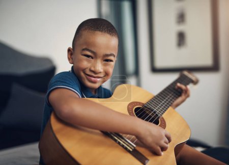 Téléchargez les photos : Il aime tout ce qui est musical. un jeune garçon jouant de la guitare à la maison - en image libre de droit