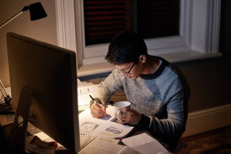 Photo for Young, man and student studying at night on a desk computer in a bedroom. College, guy and learning at apartment with coffee to study with technology and the internet for education at university - Royalty Free Image