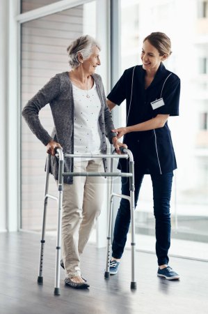 Im so proud of your progress. a female nurse assisting a senior woman using a walker
