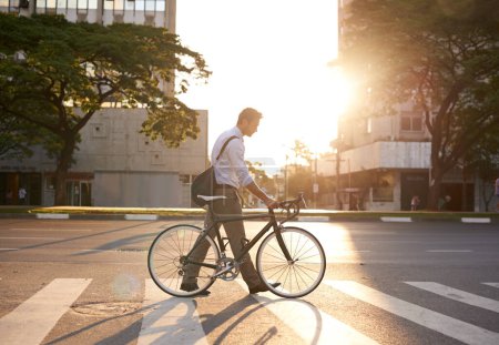 Foto de Commute, ciclista y hombre de negocios en la ciudad por la mañana, los viajes y la huella de carbono. Ciclismo, transporte y urbano con empleado masculino caminando en travesía para viaje, tránsito y profesional. - Imagen libre de derechos