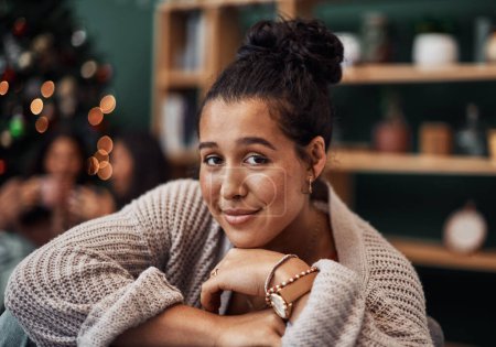 Photo for Christmas time is for curling up on the couch. a beautiful young woman relaxing on the sofa with her friends in the background during Christmas at home - Royalty Free Image