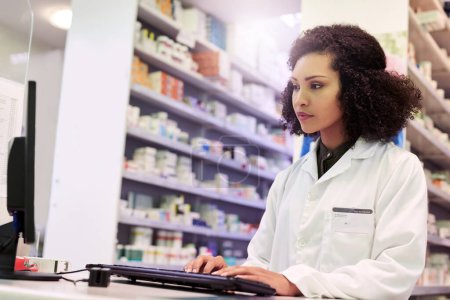 Téléchargez les photos : Vérifier quelles prescriptions sont prêtes pour les recharges. un pharmacien travaillant sur un ordinateur dans une pharmacie - en image libre de droit
