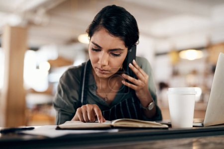 Foto de Me gustaría hacer un pedido para... una mujer joven usando un teléfono inteligente mientras trabaja en un café - Imagen libre de derechos