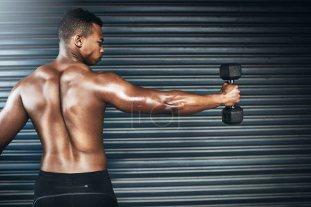 Photo for You dont find willpower - you create it. Rearview shot of a muscular young man lifting weights against a grey background - Royalty Free Image