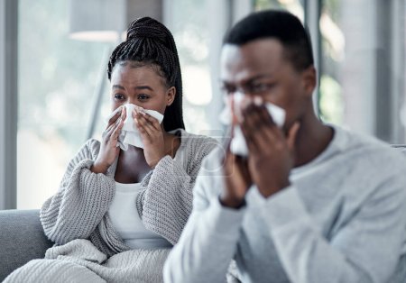 Téléchargez les photos : Chère grippe, on ne t'aime pas. un jeune couple se mouche sur le canapé à la maison - en image libre de droit