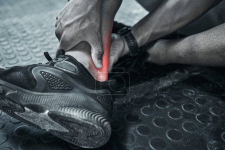 Photo for Using cgi to find pain. Closeup on hand of a trainer touching a sprained ankle. Ankle strain will cause a problem when exercising. Bodybuilder in discomfort with muscle ache. Hurt trainer in the gym. - Royalty Free Image
