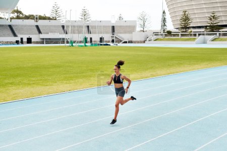 Photo for Running is my escape. Full length shot of an attractive young athlete running a track field alone during a workout session outdoors - Royalty Free Image