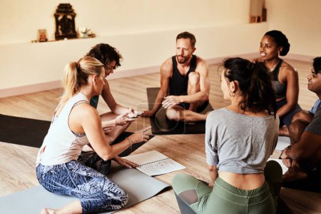 Téléchargez les photos : Le yoga est encore mieux partagé avec des amis. un groupe de jeunes hommes et femmes bavardant pendant un cours de yoga - en image libre de droit
