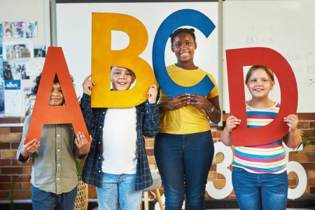 Foto de El color ayuda a los niños a aprender mejor. un grupo diverso de niños de pie y sosteniendo las letras del alfabeto en su aula en la escuela - Imagen libre de derechos