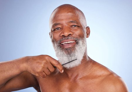 Photo for My pride grows from my chin. Studio portrait of a mature man combing his grey beard against a blue background - Royalty Free Image