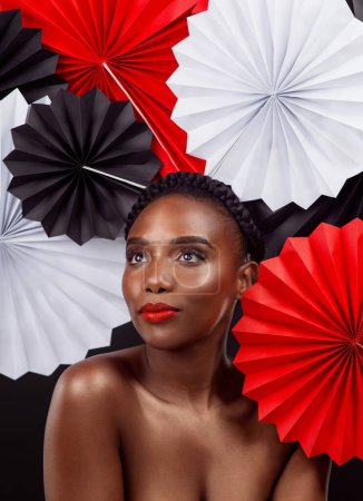 Photo for You can never go wrong with red. Studio shot of a beautiful young woman posing with a origami fans against a black background - Royalty Free Image