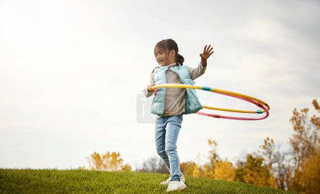 Foto de Disfrutando de un poco de diversión hula hooping. una adorable niñita pasando el día al aire libre - Imagen libre de derechos