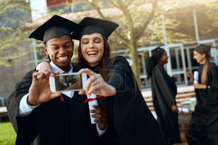 Téléchargez les photos : Diplômé avec l'amour de ma vie. un jeune homme et une jeune femme prenant des selfies avec un téléphone portable le jour de la remise des diplômes - en image libre de droit