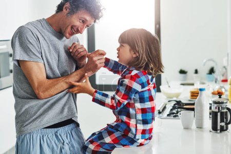 Photo for The tickle monster is coming for you. a mature father and his young son in the kitchen at home - Royalty Free Image