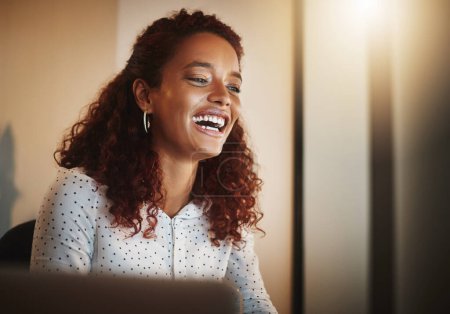 Téléchargez les photos : Productivité, l'activateur de sourire. une jeune femme d'affaires utilisant un ordinateur pendant une nuit tardive au travail dans un bureau moderne - en image libre de droit
