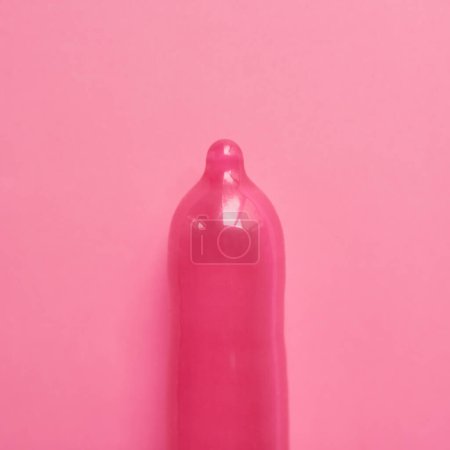 Foto de Pink te hace pensar. Estudio plano de un condón rosa colocado sobre un fondo rosa - Imagen libre de derechos